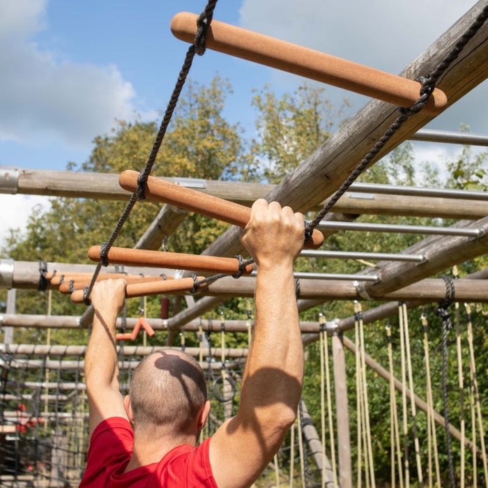 Man hangt in klimtoestel tijdens outdoor obstacle training